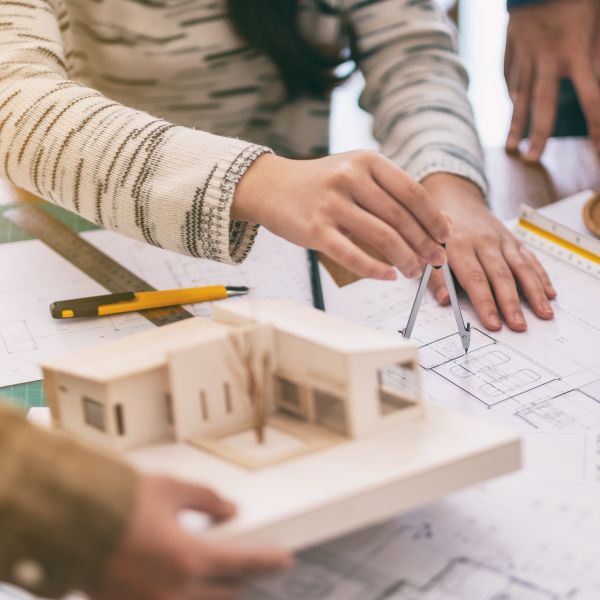 architects checking blueprint with 3D wooden model